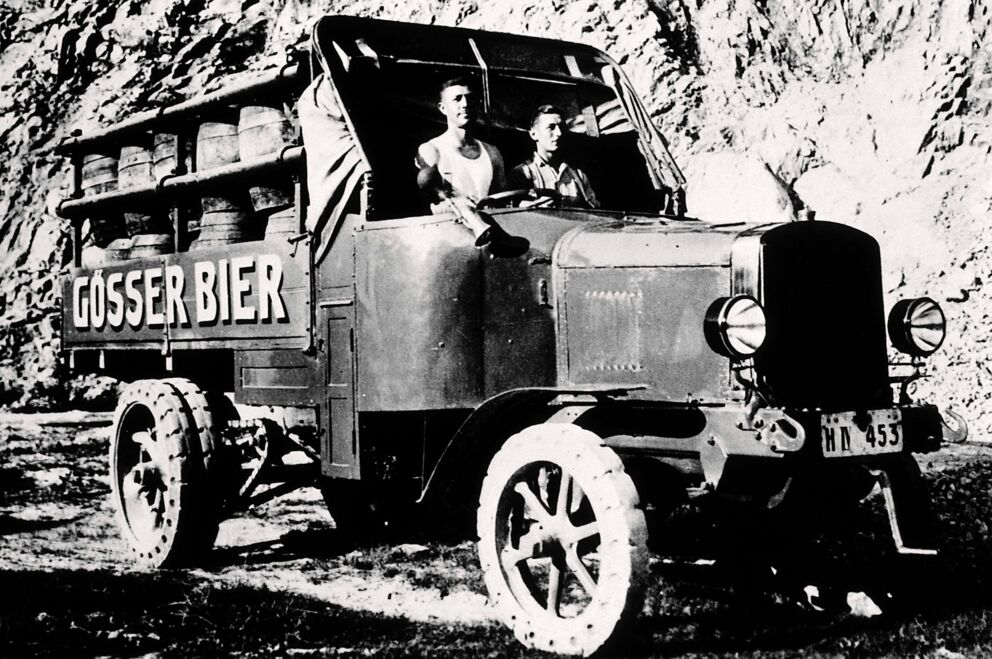 Ein altes Foto mit einem Auto, das Gösser Bierfässern transportiert