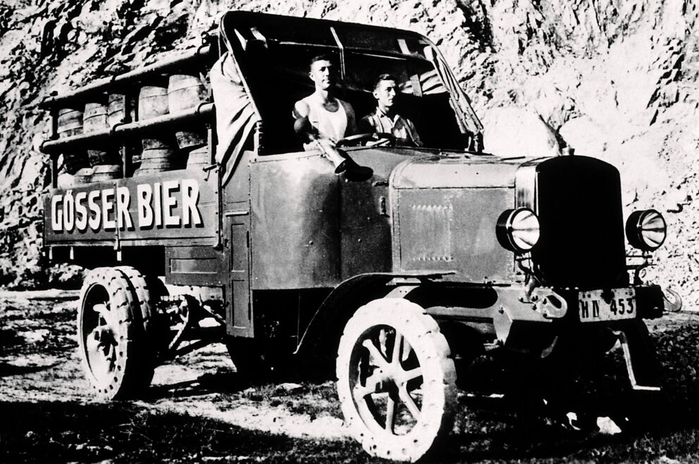 Ein altes Foto mit einem Auto, das Gösser Bierfässern transportiert