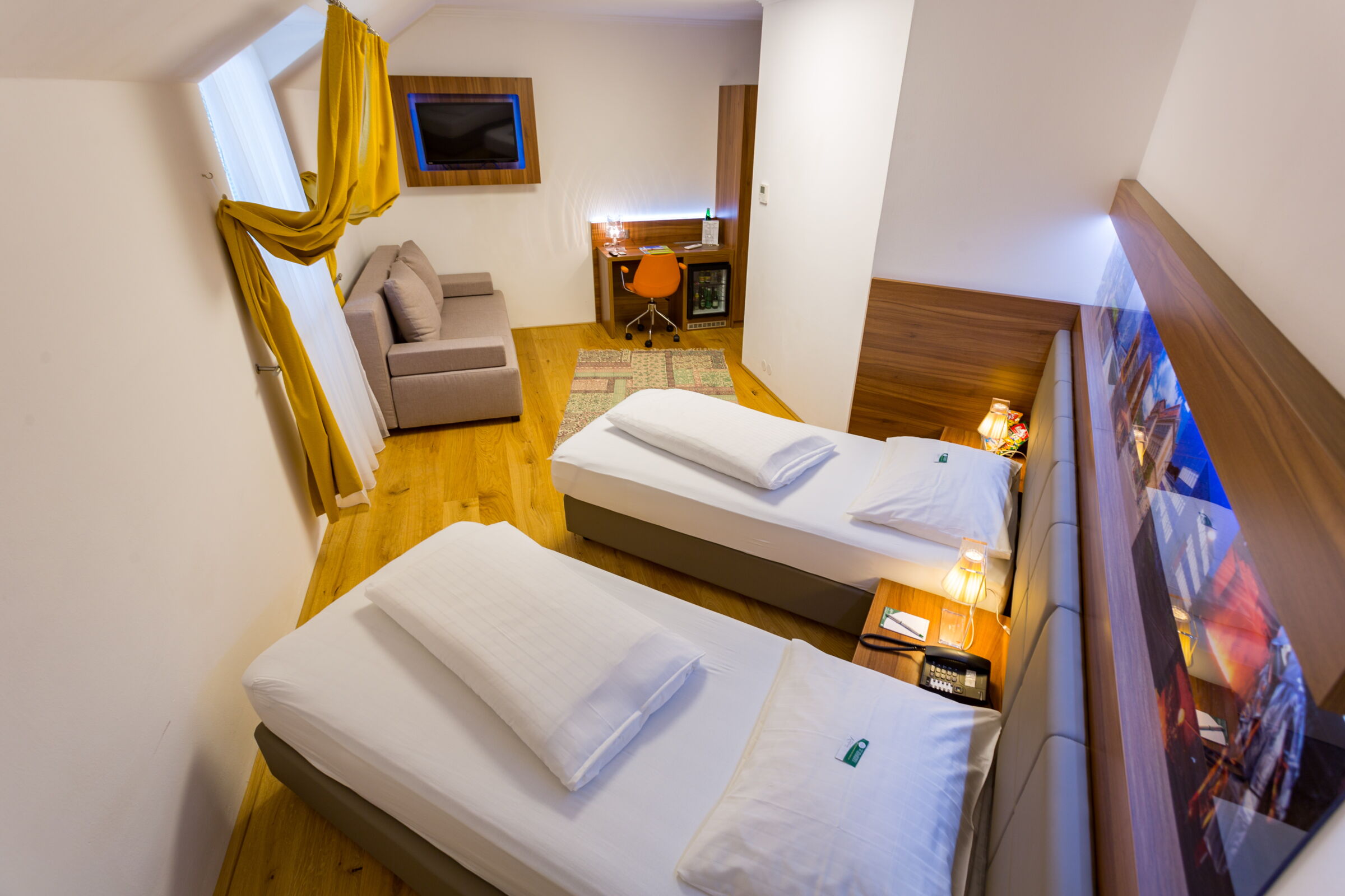2 Twin sized Betten im Business Zimmer mit Fernseher und Couch